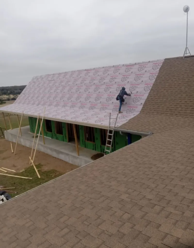 Worker preparing underlayment for a metal roof installation in Corning